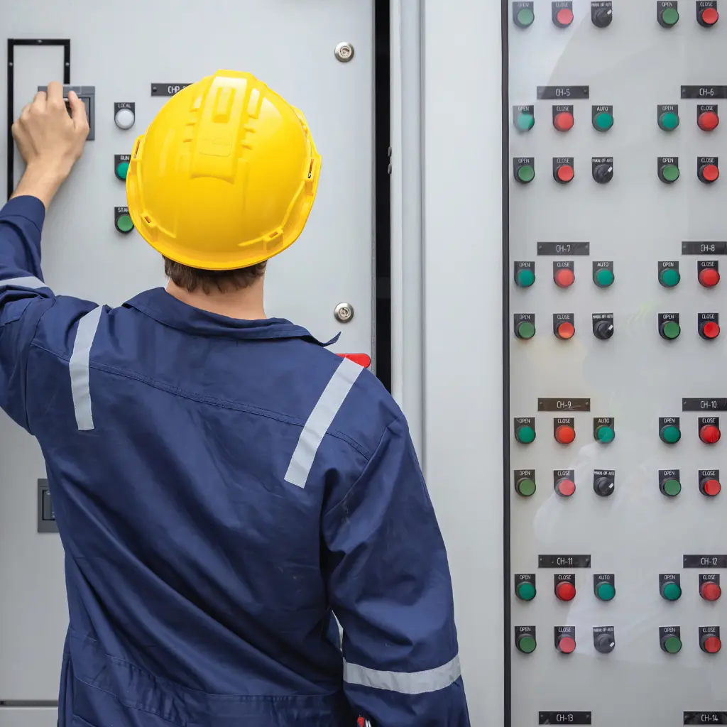 Profesyonel elektrik pano montajı yapan kasklı teknisyen ve kontrol paneli.
